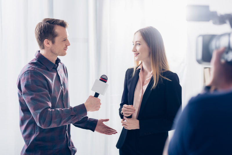 beautiful businesswoman in suit giving interview to handsome journalist in office Periodista entrevistando con una cámara a un experto